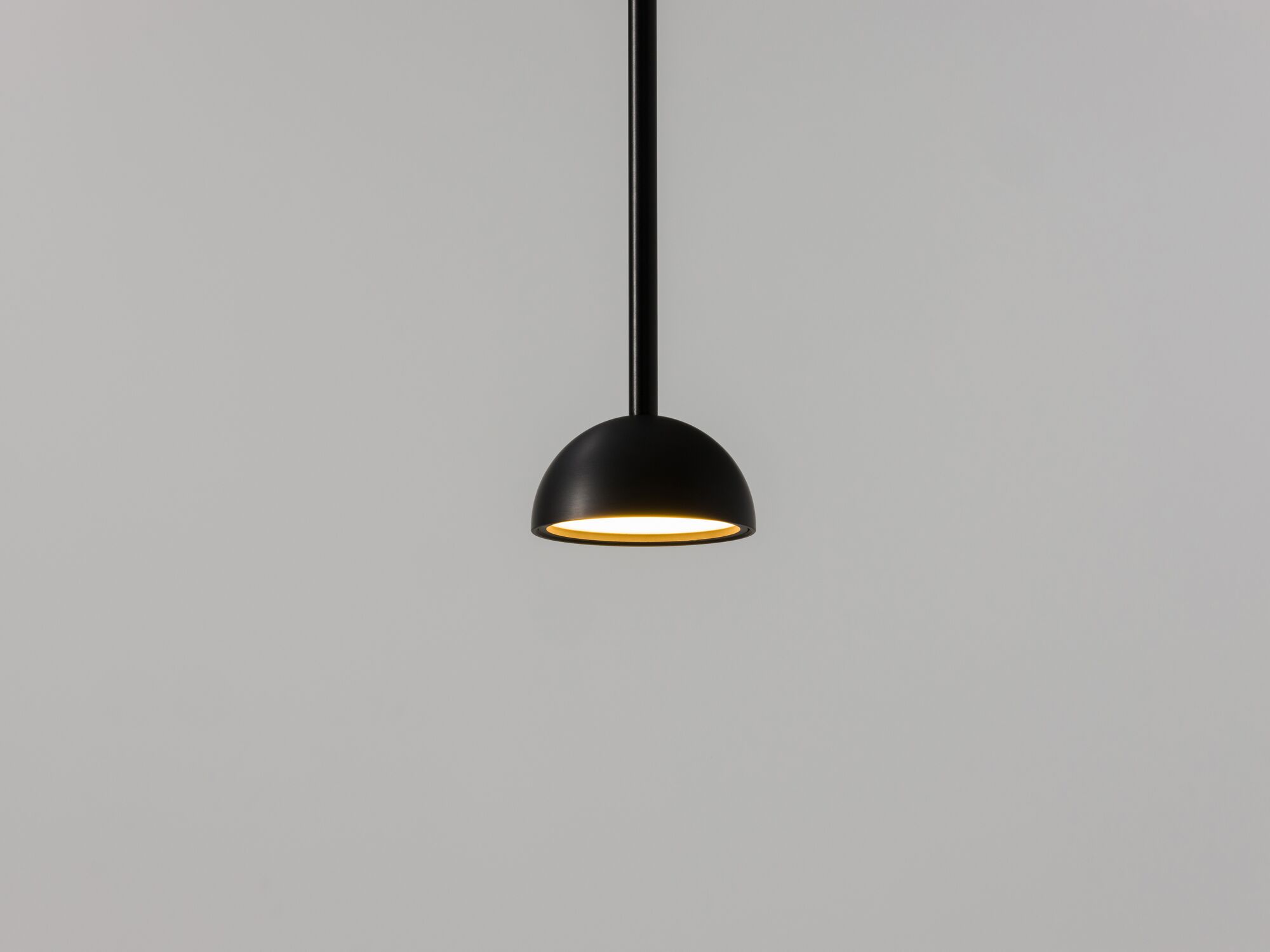 Black rounded pendant lamp with light on front view